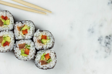 Sushi rolls prepared by professional asian chef with traditional Japanese ingredients. Salmon, rice, vegetables, sesame seeds. 