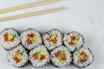 Sushi rolls prepared by professional asian chef with traditional Japanese ingredients. Salmon, rice, vegetables, sesame seeds. 