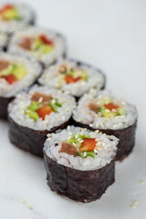 Sushi rolls prepared by professional asian chef with traditional Japanese ingredients. Salmon, rice, vegetables, sesame seeds. 