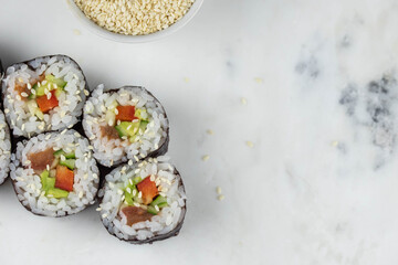 Sushi rolls prepared by professional asian chef with traditional Japanese ingredients. Salmon, rice, vegetables, sesame seeds. 