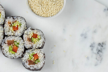 Sushi rolls prepared by professional asian chef with traditional Japanese ingredients. Salmon, rice, vegetables, sesame seeds. 
