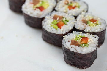 Sushi rolls prepared by professional asian chef with traditional Japanese ingredients. Salmon, rice, vegetables, sesame seeds. 