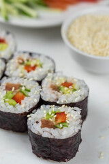 Sushi rolls prepared by professional asian chef with traditional Japanese ingredients. Salmon, rice, vegetables, sesame seeds. Sushi cooking and making concept