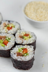 Sushi rolls prepared by professional asian chef with traditional Japanese ingredients. Salmon, rice, vegetables, sesame seeds. Sushi cooking and making concept