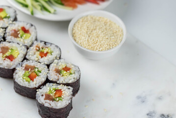 Sushi rolls prepared by professional asian chef with traditional Japanese ingredients. Salmon, rice, vegetables, sesame seeds. Sushi cooking and making concept