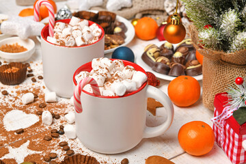 sweet food top view background for merry christmas or new year holiday decoration - chocolate candies, tangerines, cookies, marshmallow and cocoa latte on white wood