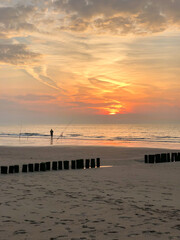 Fototapeta premium Angler bei Sonnenuntergang an der Niederländischen Nordsee