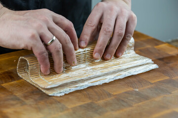 Closeup of chef hands preparing japanese food. Professional chef making sushi at restaurant. Man hands making traditional asian sushi rolls on cutting board.