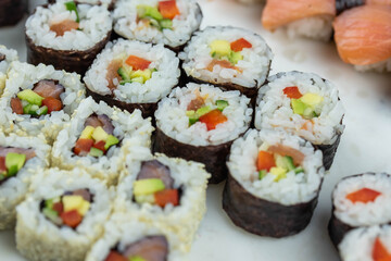 Sushi rolls prepared by professional asian chef with traditional Japanese ingredients. Salmon, rice, vegetables, sesame seeds. 