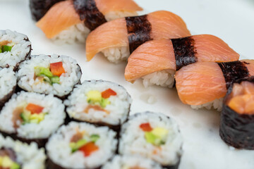 Sushi rolls prepared by professional asian chef with traditional Japanese ingredients. Salmon, rice, vegetables, sesame seeds. 