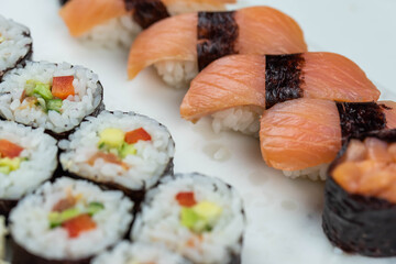 Sushi rolls prepared by professional asian chef with traditional Japanese ingredients. Salmon, rice, vegetables, sesame seeds. 