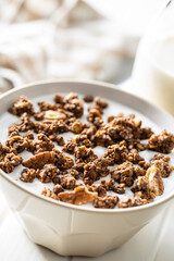 Chocolate breakfast cereal. Morning granola with milk in bowl.