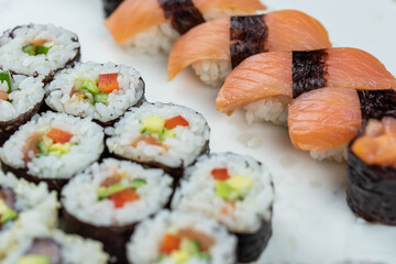 Sushi rolls prepared by professional asian chef with traditional Japanese ingredients. Salmon, rice, vegetables, sesame seeds. 