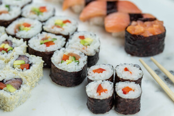Sushi rolls prepared by professional asian chef with traditional Japanese ingredients. Salmon, rice, vegetables, sesame seeds. 