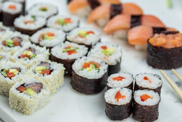 Sushi rolls prepared by professional asian chef with traditional Japanese ingredients. Salmon, rice, vegetables, sesame seeds. 