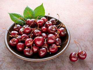 Fresh ripe red cherries on a clay plate on a dark blue background. The concept of healthy nutrition. Vegetarian food