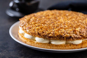  Sweet almond cake. Pie with cream and almonds on black table.