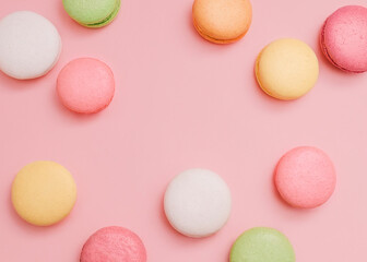 Macaroons Cute top view photo with copy space White, yellow, pink, orange, and green french cookies on pink background