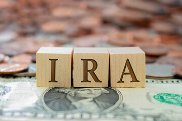 Wooden block with the letter IRA with some money around. Concept: Retirement Plan in USA,...