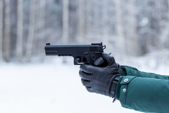 Gun in hand. Black leather gloves with a pistol. Shooting in nature.