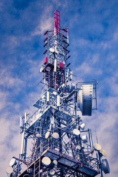 Telecommunication tower with antennas against the blue cloudy sky