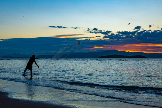 Our daily fish. Silhouette of a fisherman throwing the fishing net, called "tarrafa" on the Sambaqui beach in Florian&oacute;polis.