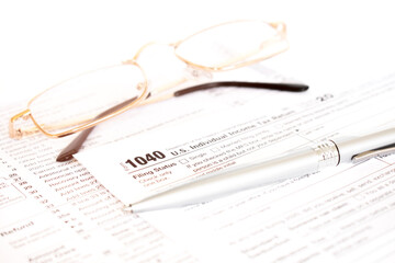 Tax form business financial concept with a pair of gold glasses and a pen aside.