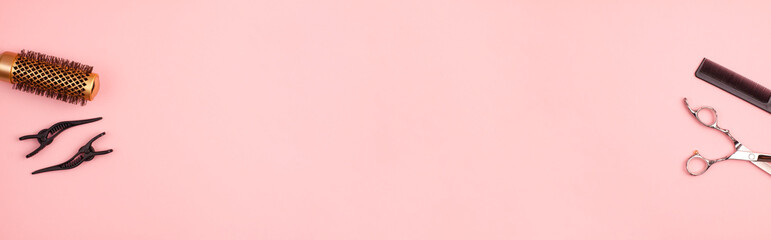 Banner flat lay of professional hair cutting shears, gold round hair brush for styling, comb for separating hair and section hair clips template on pink background. Hairdresser salon equipment