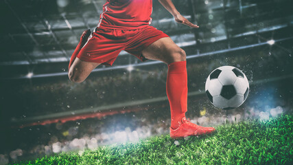Close up of a soccer scene at night match with player in a red uniform kicking the ball with power - obrazy, fototapety, plakaty
