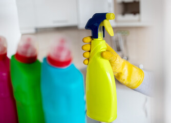 Woman taking spray bottle from shelf in pantry