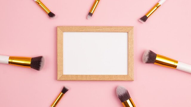 Stop motion animation mockup wooden picture frame top view of cosmetics brushes set for makeup on pink background. Cosmetics and beauty concept template. Make up concept with copy space flat lay.