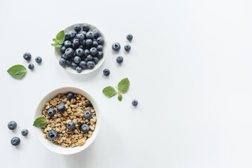 Breakfast with muesli, fresh berries blueberries on white background. Healthy food concept. Flat lay, top view, copy space.