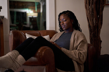 Black woman comfortable and cozy in chair of cellphone