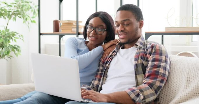 Couple using laptop on sofa at home - Powered by Adobe