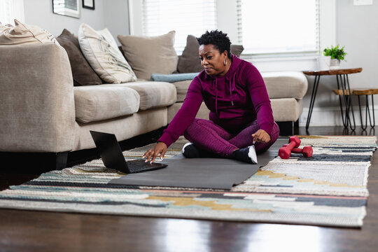 Black woman exercises while watching online tutorial fitness class