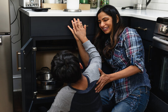 Mother and son high five after successfully repairing cabinets, Home improvement
