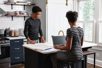 Black mother talking with son in kitchen at home