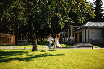 Fototapeta premium loving young couple having fun outdoors in summer sunny day. Man and woman are running near cafe in park. valentines day
