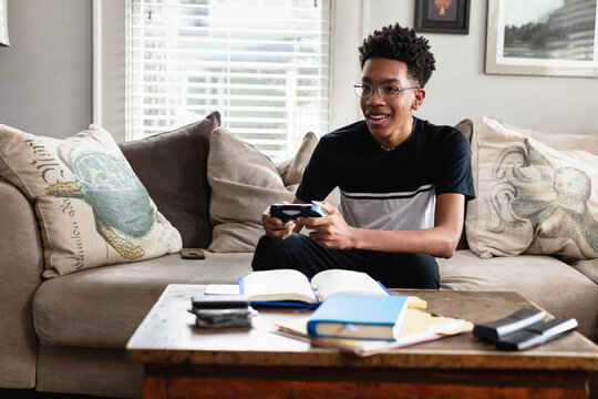 Teenage boy plays video games at home in family room