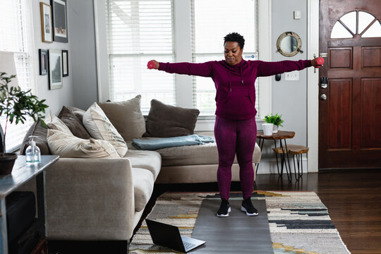 Black woman exercises while watching online tutorial fitness class