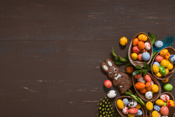 Easter eggs hunt concept background with chocolate eggs and bunny on wooden table copy space. View from above