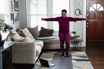 Black woman exercises while watching online tutorial fitness class