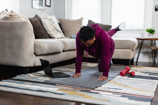 Black woman exercises while watching online tutorial fitness class