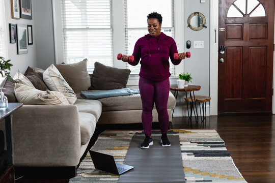 Black woman exercises while watching online tutorial fitness class