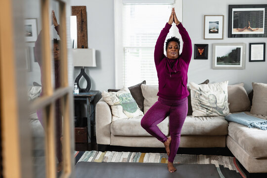 Black woman does tree yoga pose, at home fitness and wellness, centered strength