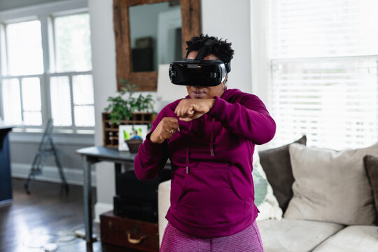 African American woman doing virtual reality VR boxing at home in living room