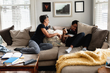 Black mother and son laughing together on couch, loving moment