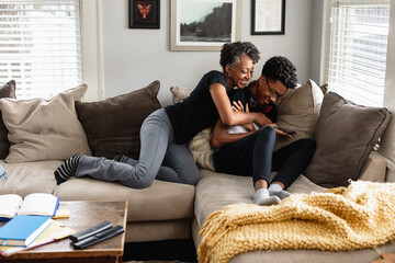 Black mother and son laughing together on couch, loving moment