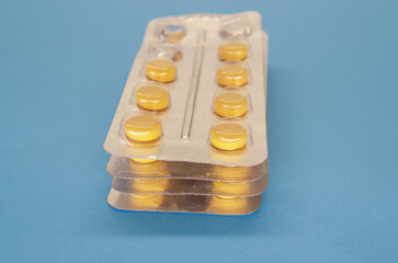 Stack of yellow pills in blisters on a blue background