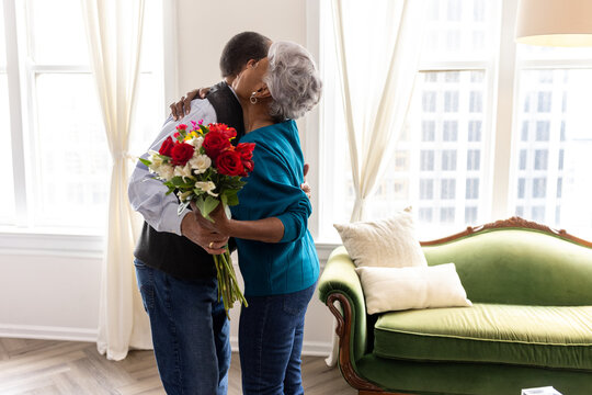 Senior couple celebrating wedding anniversary with roses at home, love connection